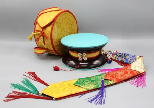 Damaru de chod o kusali y su funda en un fondo azul.