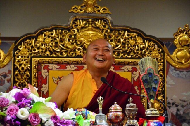 Se ve a Tulku Pema Rigtsal Rinpoche riendo en un trono de león típico del budismo tibetano.